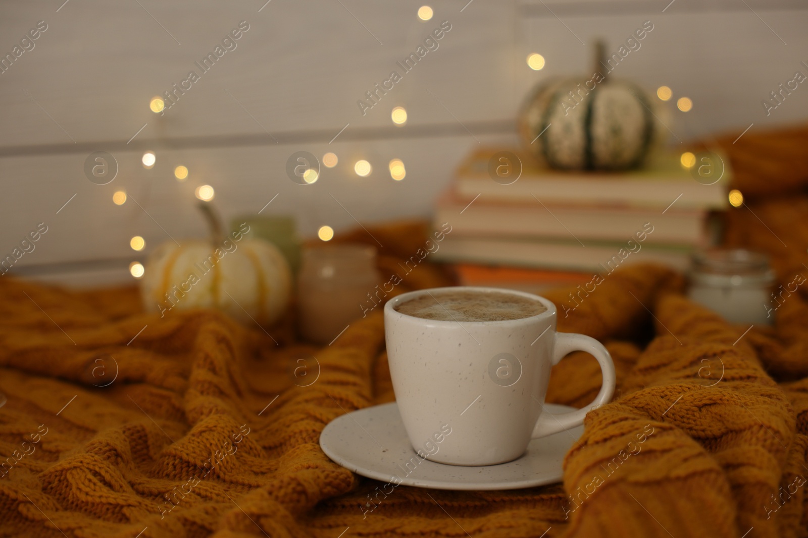 Photo of Cup of coffee on soft sweater, space for text. Autumn atmosphere