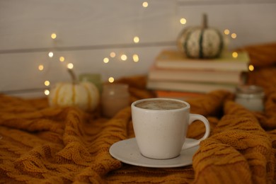 Cup of coffee on soft sweater, space for text. Autumn atmosphere