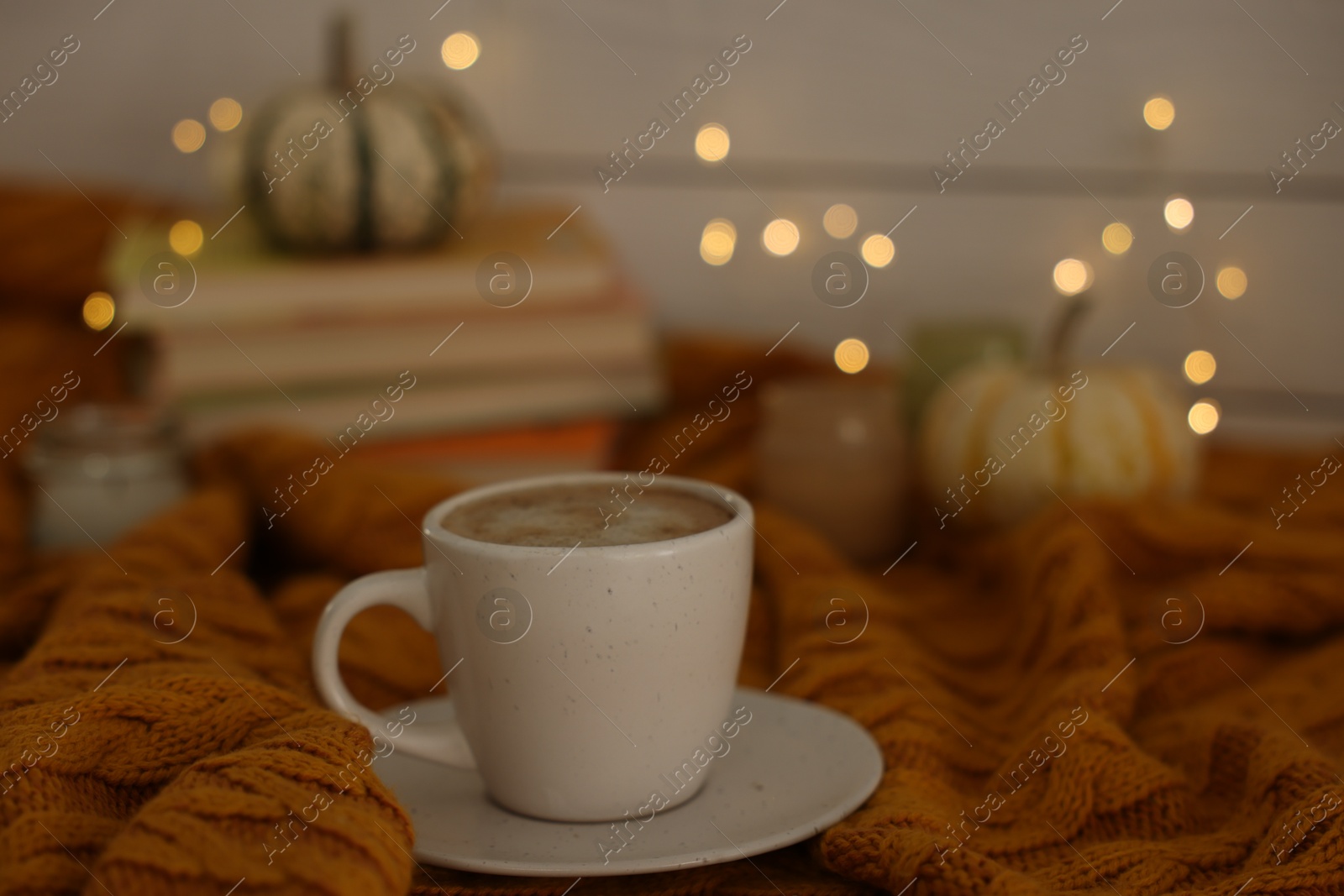 Photo of Cup of coffee on soft sweater, closeup. Autumn atmosphere