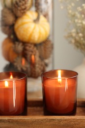 Photo of Tray with burning candles and autumn decor indoors, closeup