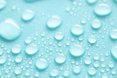 Photo of Water drops on turquoise background, closeup view