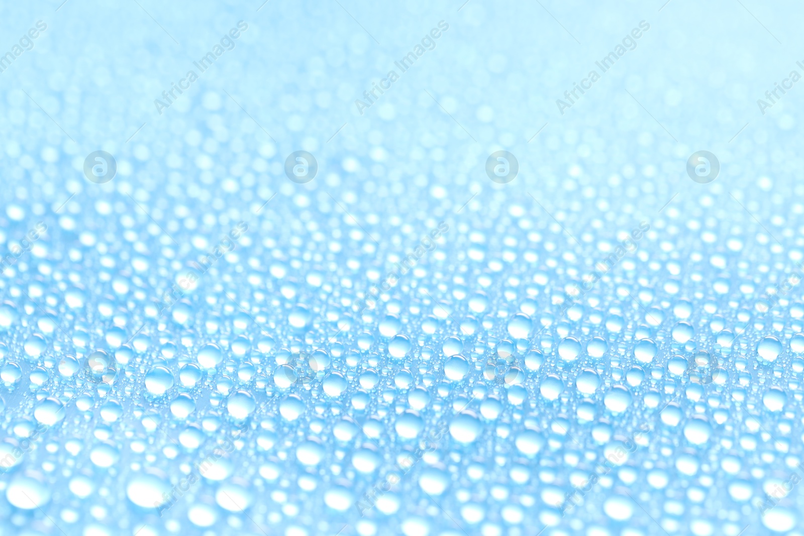 Photo of Water drops on light blue background, closeup view