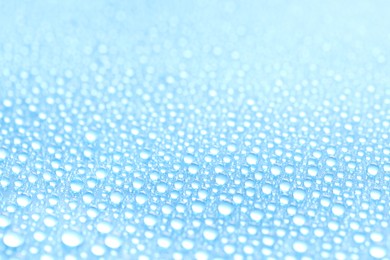 Photo of Water drops on light blue background, closeup view