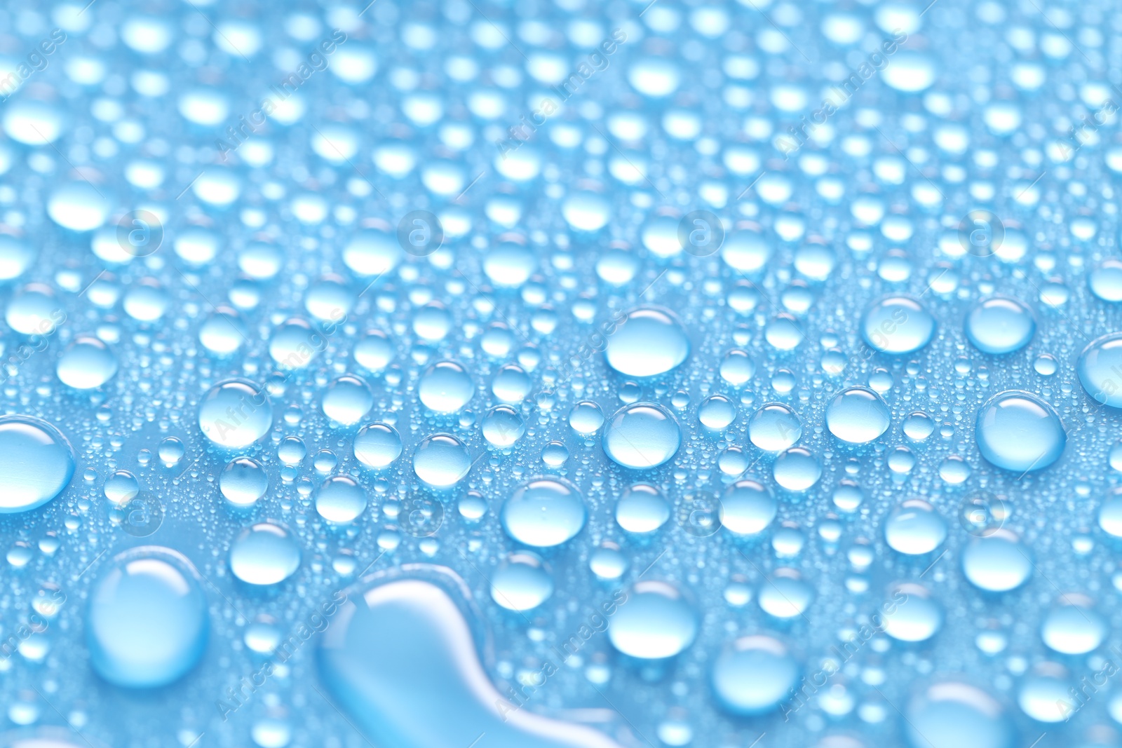 Photo of Water drops on light blue background, closeup view