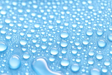 Photo of Water drops on light blue background, closeup view