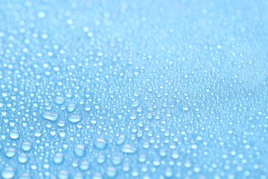 Photo of Water drops on light blue background, closeup view