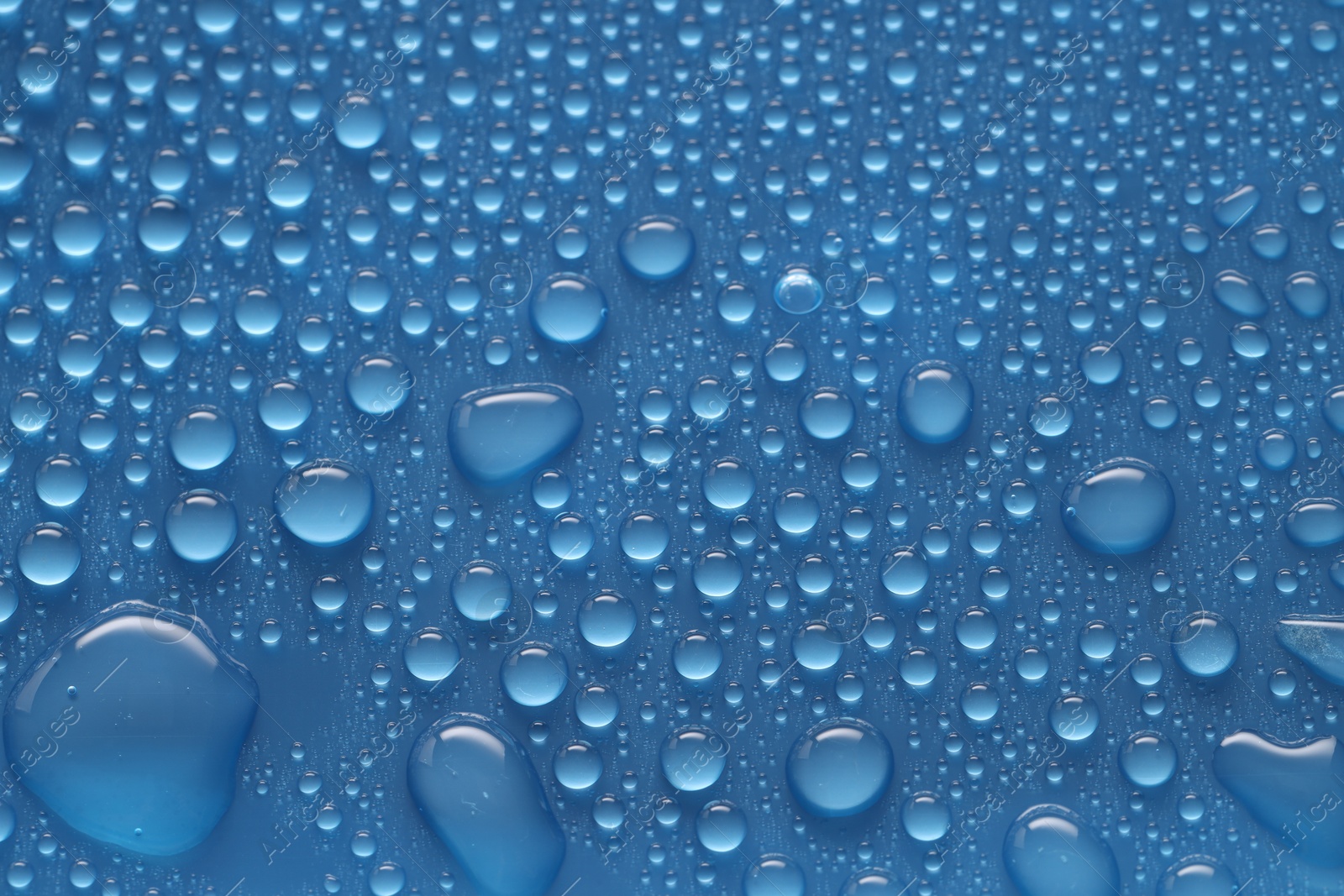 Photo of Water drops on blue background, above view