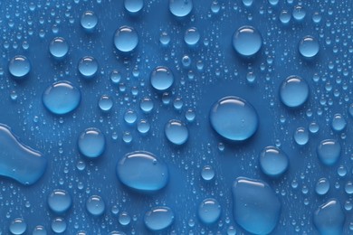 Photo of Water drops on blue background, above view