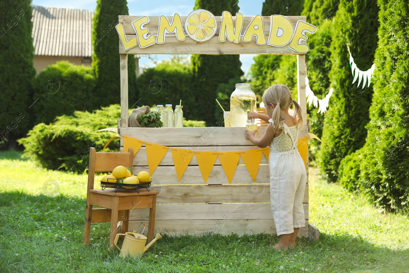 Photo of Little girl pouring natural lemonade into paper cup in park