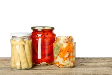 Photo of Different pickled products in jars on wooden table against white background