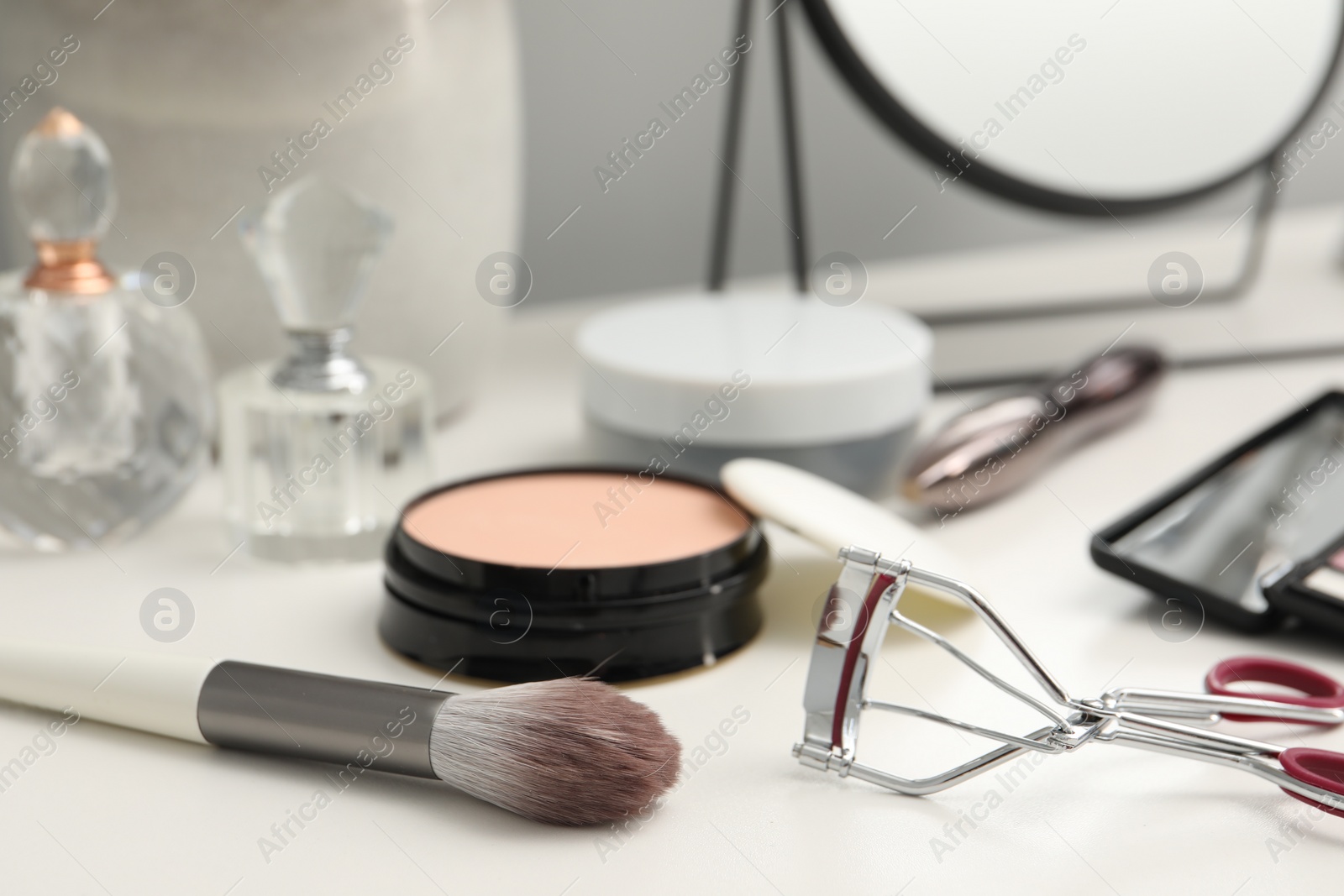Photo of Brush, mirror and cosmetic products on dressing table, closeup