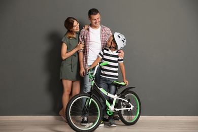 Photo of Portrait of parents and their son with bicycle near color wall