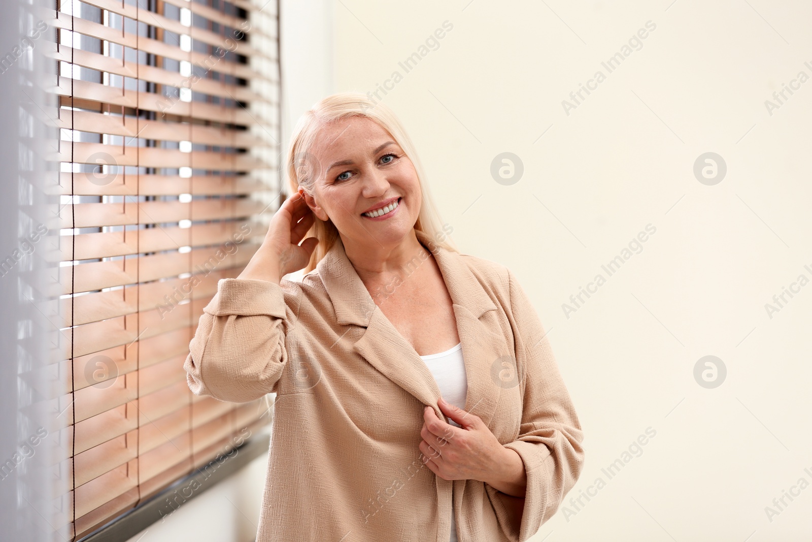 Photo of Portrait of happy mature woman near window indoors