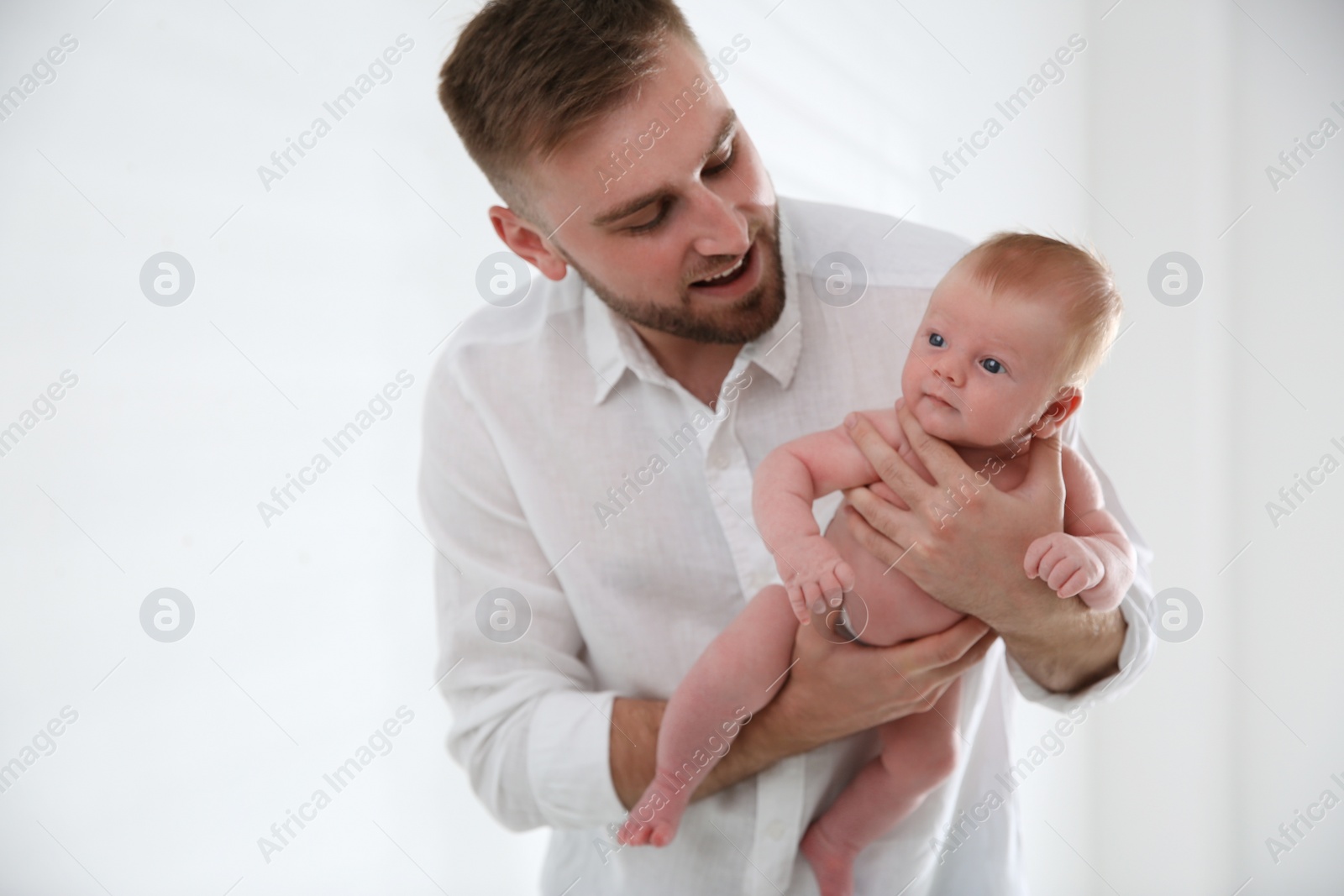 Photo of Father with his newborn son on light background