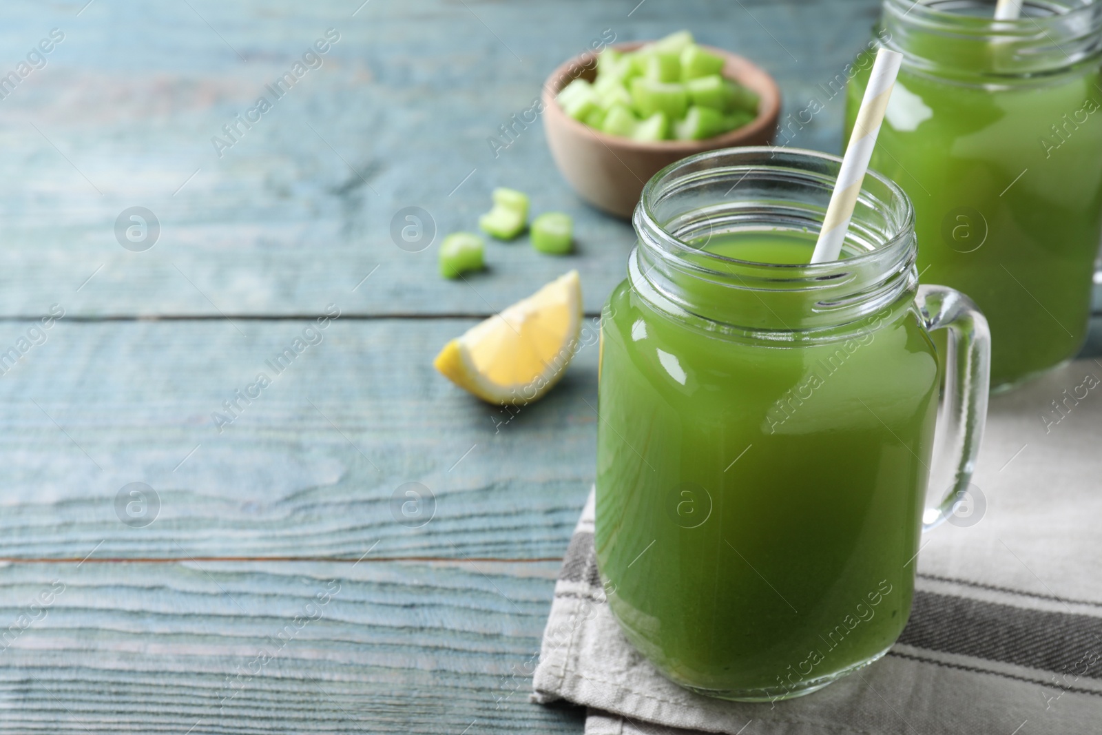 Photo of Fresh celery juice in mason jar on blue wooden table, closeup. Space for text