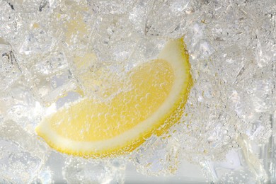 Photo of Juicy lemon slice and ice cubes in soda water on white background, closeup