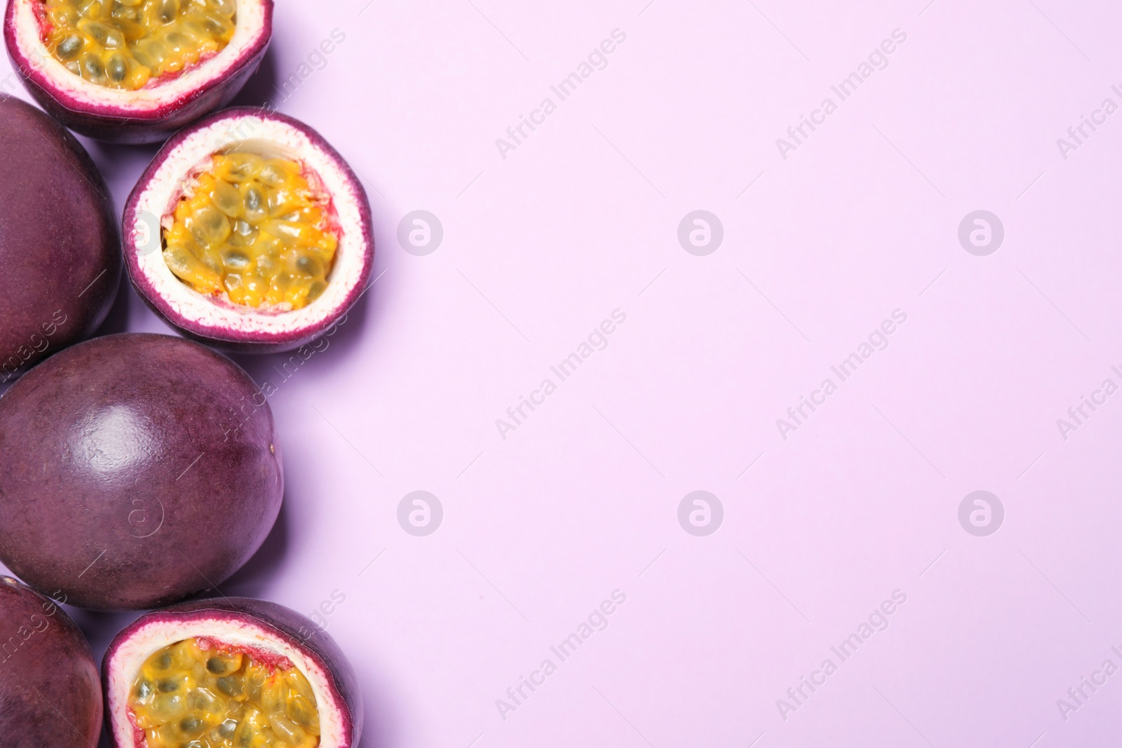 Photo of Fresh ripe passion fruits (maracuyas) on light pink background, flat lay. Space for text