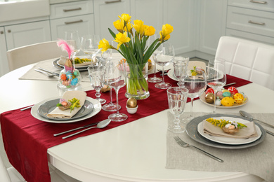 Photo of Festive Easter table setting with floral decor in kitchen