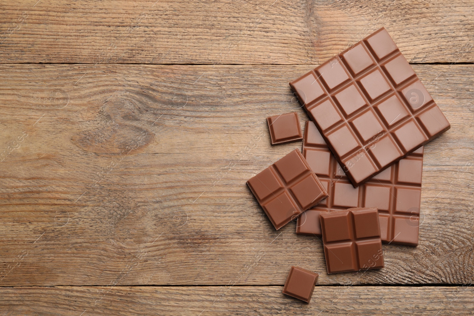 Photo of Delicious milk chocolate on wooden table, flat lay. Space for text