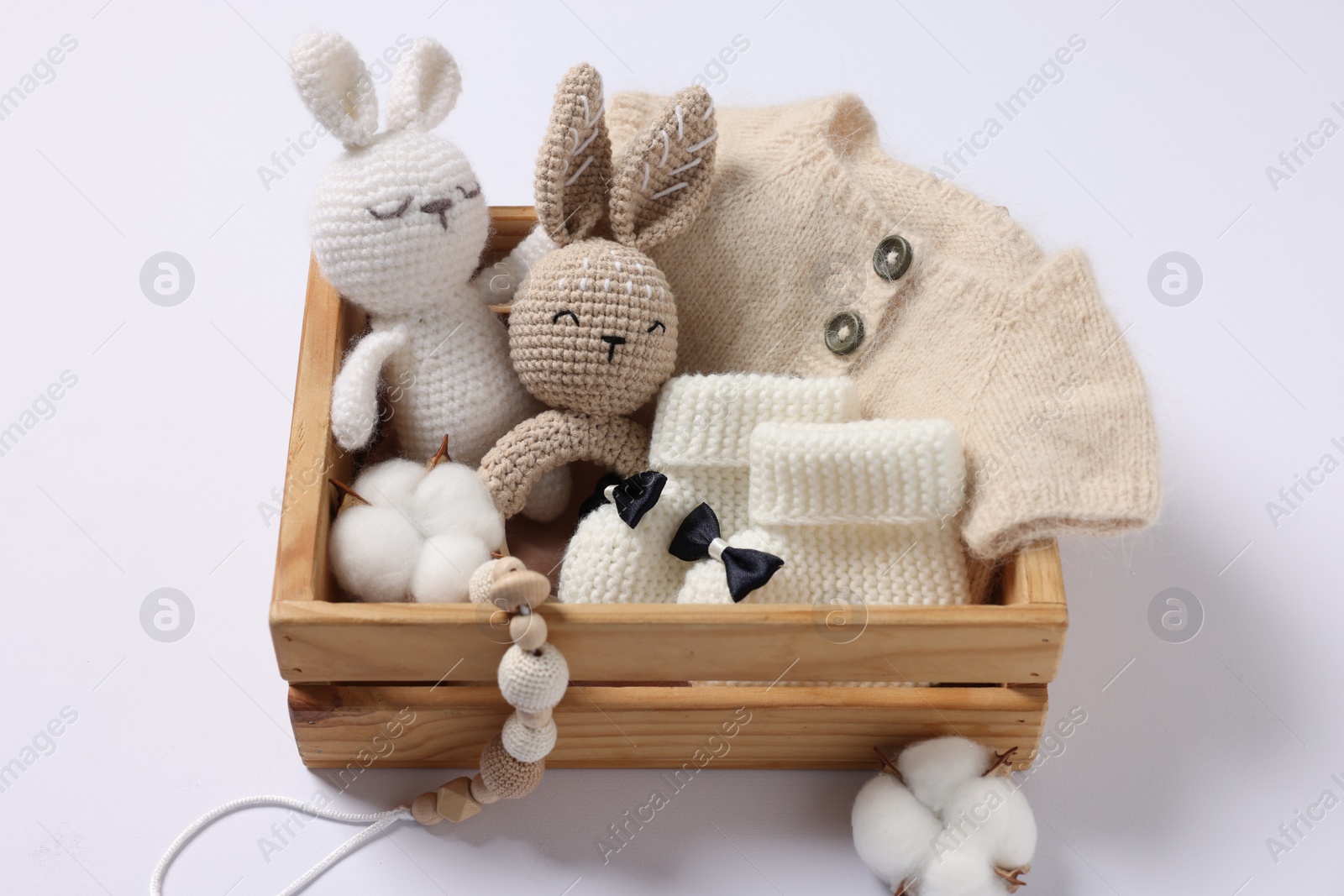 Photo of Different baby accessories and clothes in wooden crate on white background