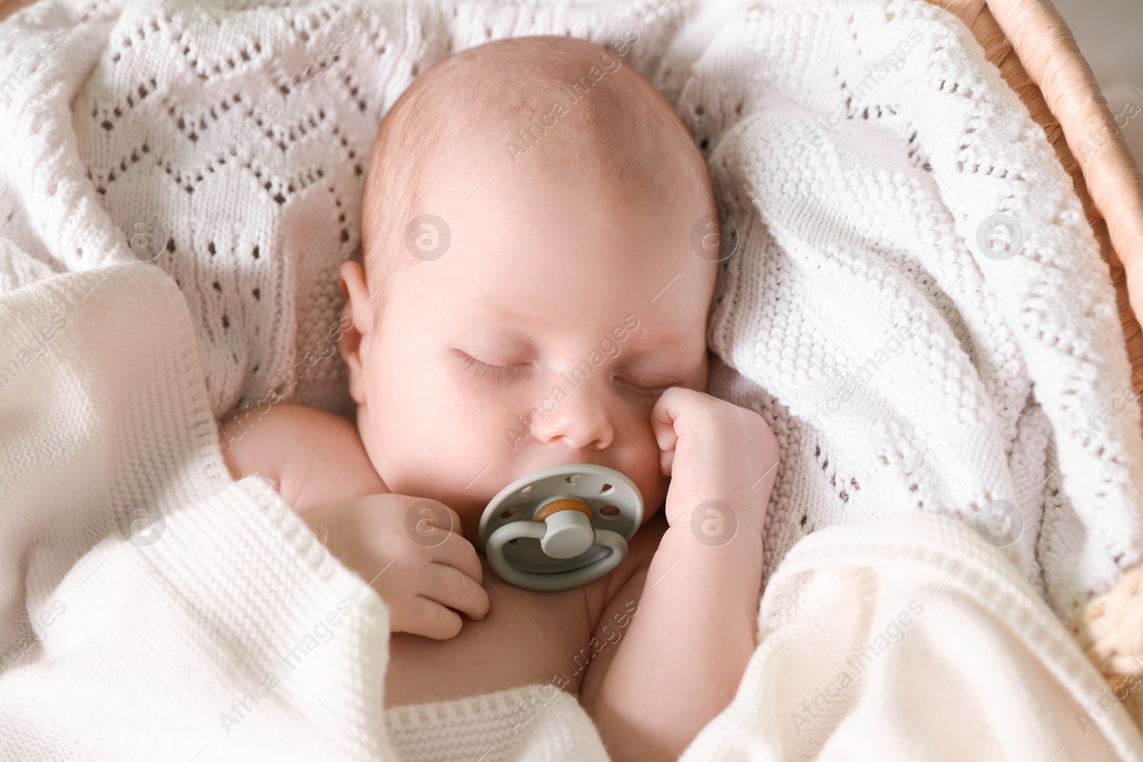 Photo of Cute newborn baby with pacifier sleeping on white blanket, top view