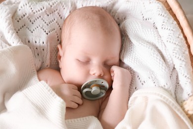 Photo of Cute newborn baby with pacifier sleeping on white blanket, top view