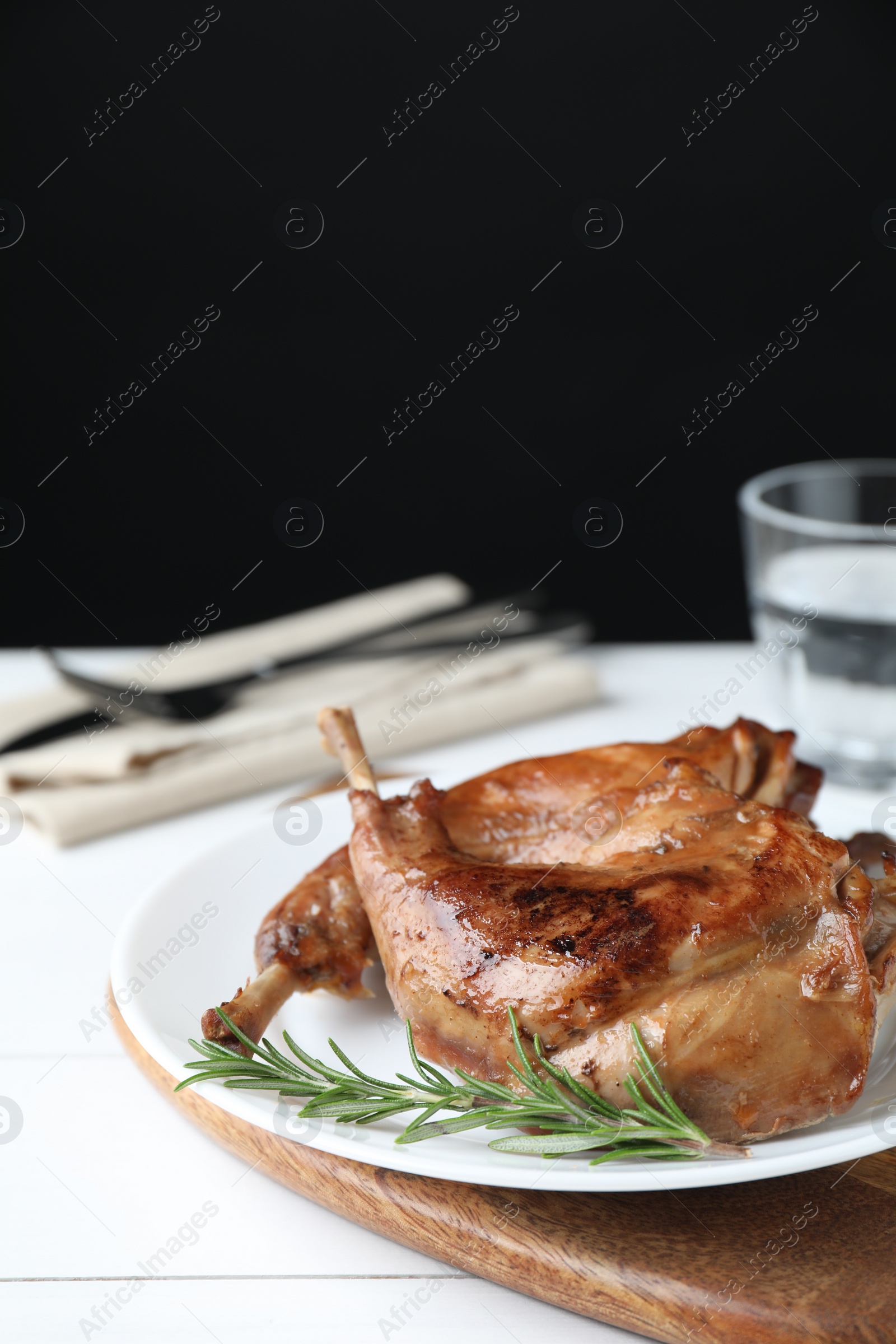 Photo of Tasty cooked rabbit meat with rosemary on white table, space for text