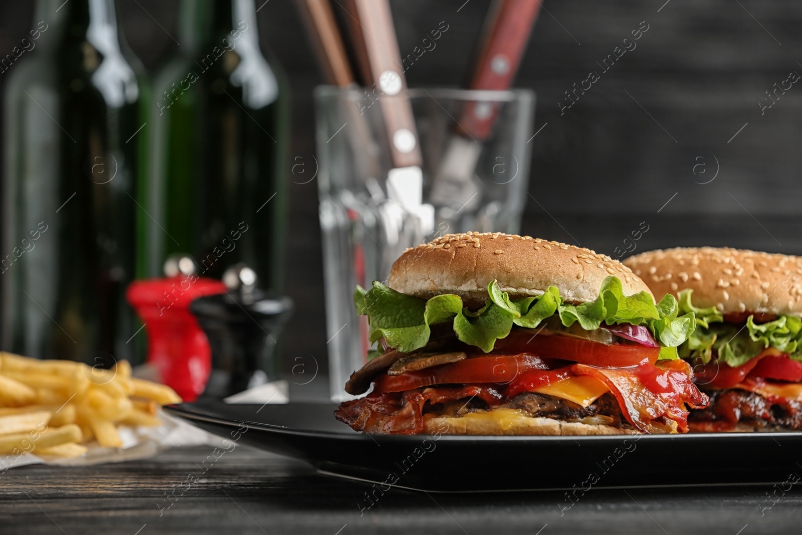 Photo of Plate with tasty burgers on wooden table. Space for text