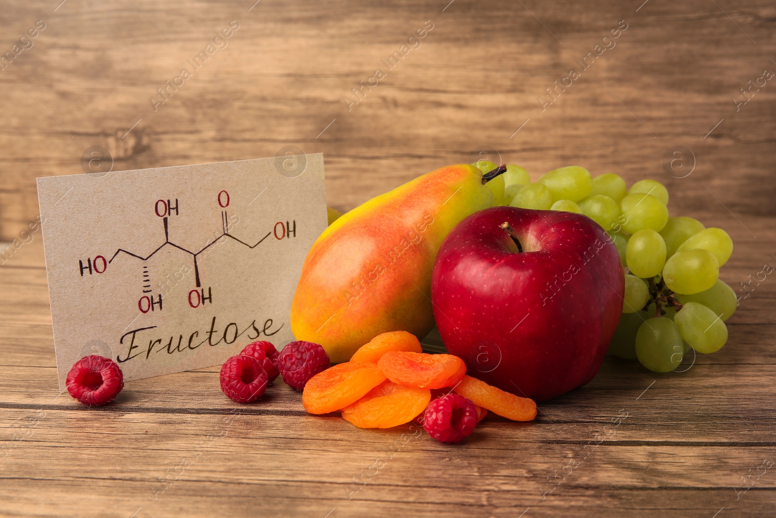 Photo of Card with word Fructose, delicious ripe fruits, raspberries and dried apricots on wooden table