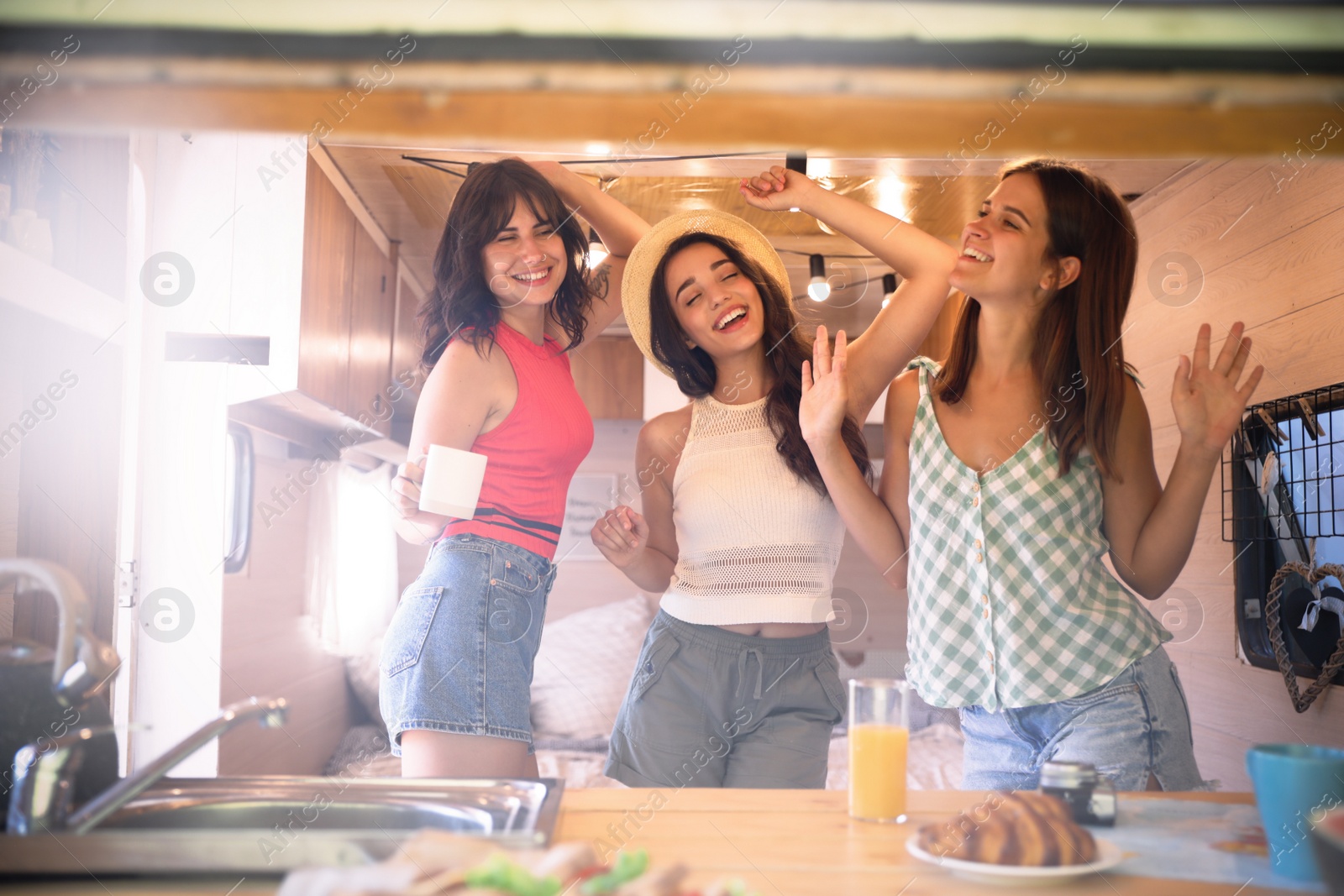 Photo of Happy young women dancing in trailer. Camping vacation