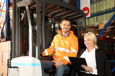 Photo of Happy manager near worker in forklift truck at warehouse