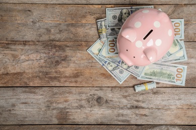 Photo of Piggy bank with money and space for text on wooden background, top view