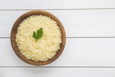 Photo of Tasty couscous with parsley on white wooden table, top view. Space for text