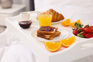 Photo of Tray with delicious breakfast on bed, closeup