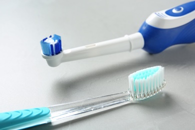 Photo of Electric and manual toothbrushes on gray background