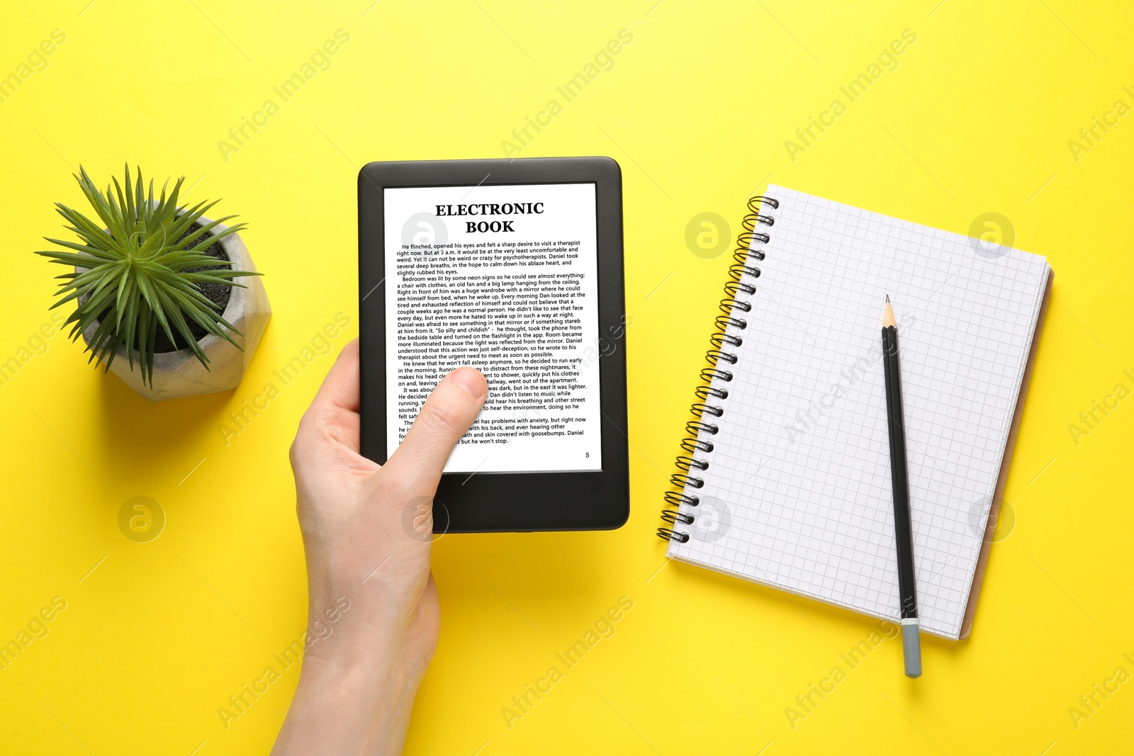 Image of Woman using e-book reader on yellow background, top view