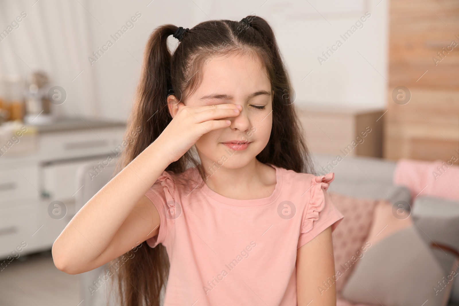 Photo of Little girl rubbing eye at home. Annoying itch