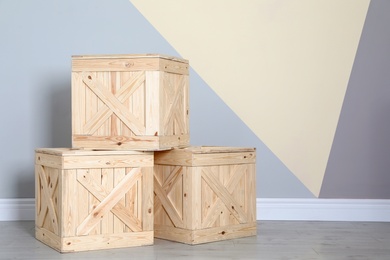 Photo of Wooden crates on floor at color wall. Space for text