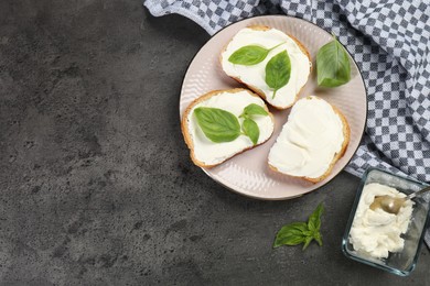 Photo of Delicious sandwiches with cream cheese and basil leaves on grey table, flat lay. Space for text