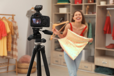 Fashion blogger recording new video in room, focus on camera