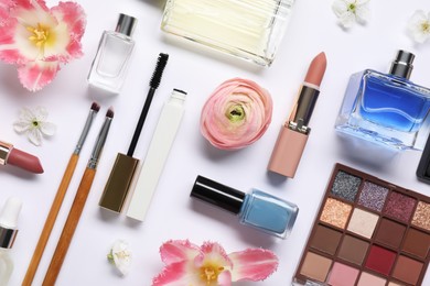 Photo of Flat lay composition with different makeup products and beautiful spring flowers on white background