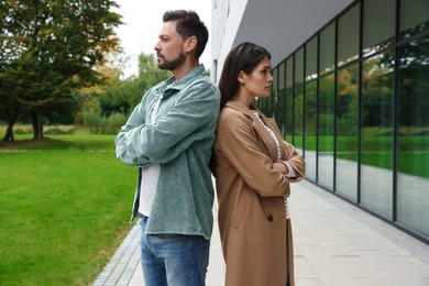 Upset arguing couple near building outdoors. Relationship problems