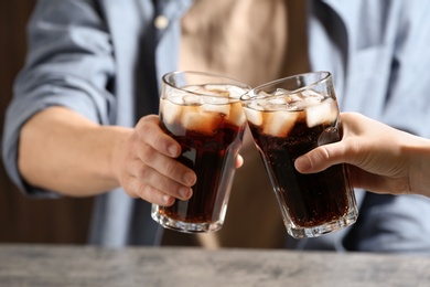 Photo of Couple with glasses of cold cola at table, closeup