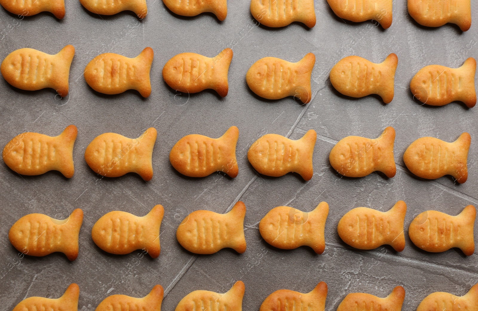 Photo of Delicious goldfish crackers on grey table, flat lay