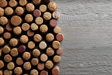 Photo of Flat lay composition with many corks of wine bottles on light grey wooden table. Space for text