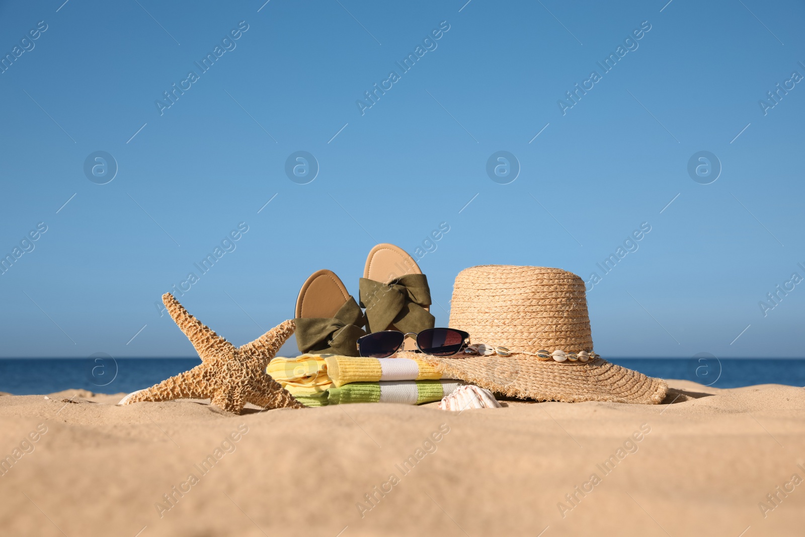 Photo of Stylish beach accessories on sand near sea