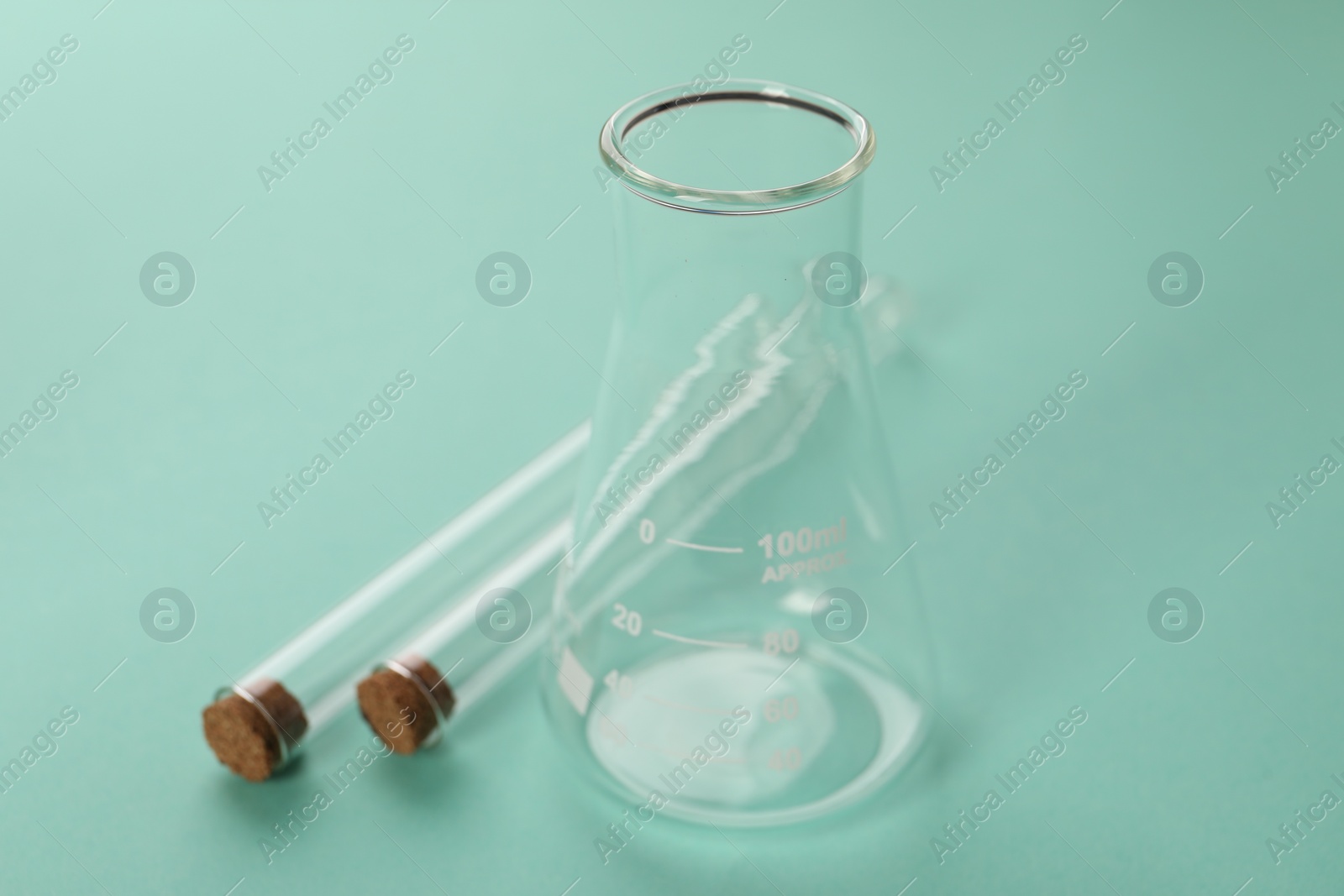 Photo of Flask and test tubes on turquoise background. Laboratory glassware