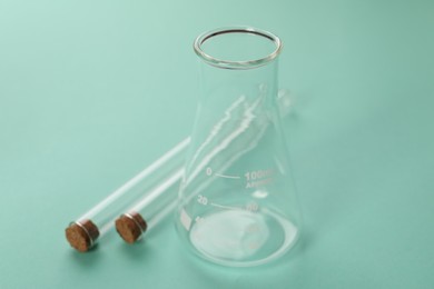 Flask and test tubes on turquoise background. Laboratory glassware