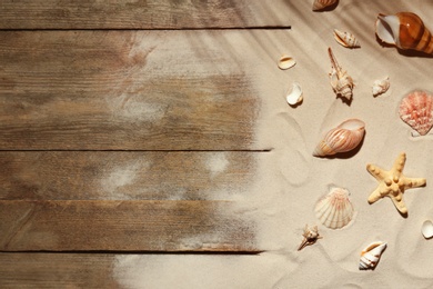 Flat lay composition with seashells, beach sand and space for text on wooden background