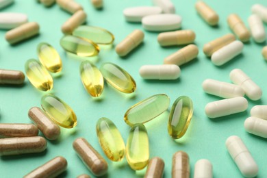 Different vitamin capsules on turquoise background, closeup